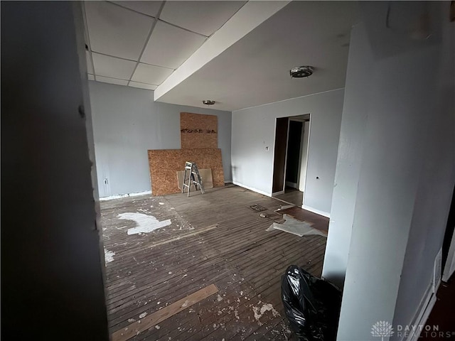 unfurnished living room featuring a paneled ceiling and dark hardwood / wood-style flooring