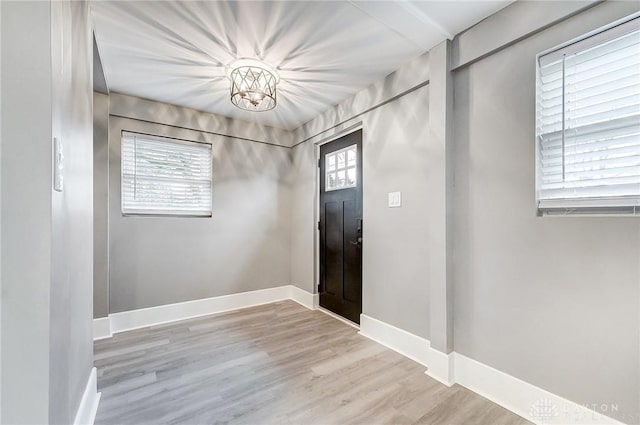 foyer entrance featuring a chandelier, light wood-type flooring, and a healthy amount of sunlight