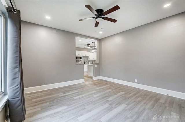 empty room featuring light wood-type flooring, ceiling fan, and sink