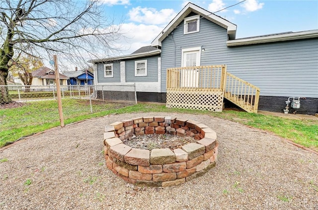 rear view of property featuring a lawn and a fire pit