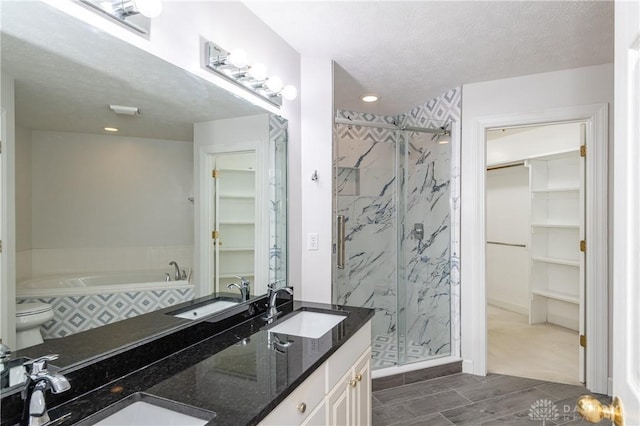 full bath with a marble finish shower, a walk in closet, and a sink