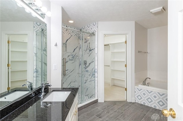 full bath with a marble finish shower, a walk in closet, wood finish floors, a garden tub, and vanity