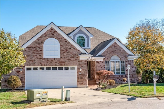 traditional-style house with driveway, roof with shingles, a front lawn, a garage, and brick siding