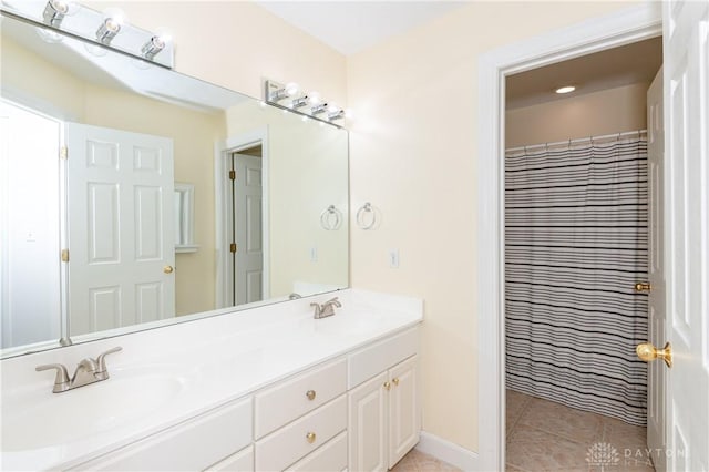 full bath featuring double vanity, baseboards, tile patterned floors, and a sink