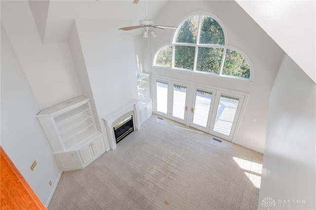 unfurnished living room featuring a glass covered fireplace, carpet flooring, and a healthy amount of sunlight