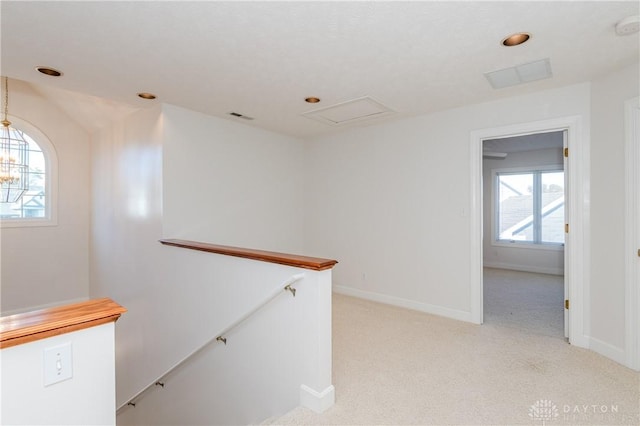 hallway with visible vents, an upstairs landing, light carpet, baseboards, and a chandelier