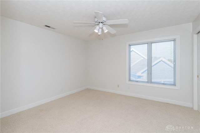 unfurnished room featuring visible vents, light carpet, a textured ceiling, and baseboards