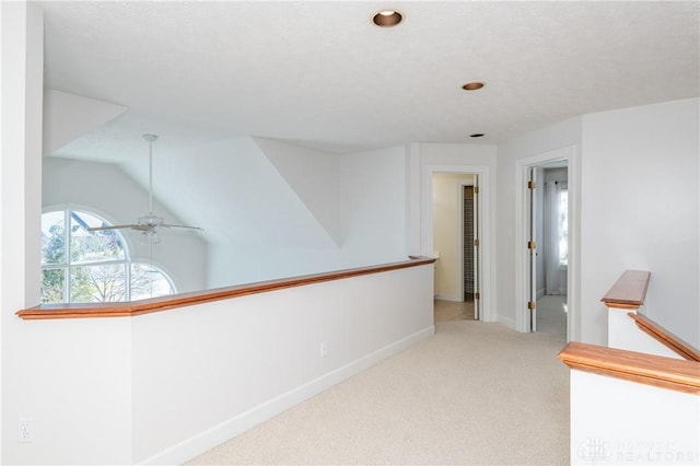 corridor with baseboards, an upstairs landing, carpet flooring, and vaulted ceiling