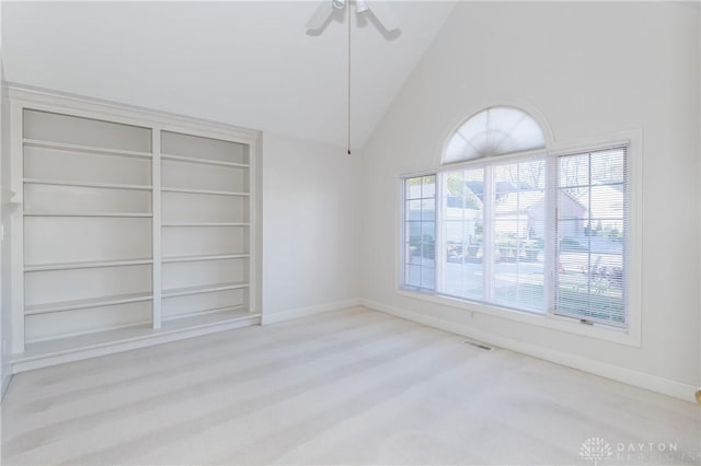 empty room featuring visible vents, built in shelves, high vaulted ceiling, baseboards, and ceiling fan