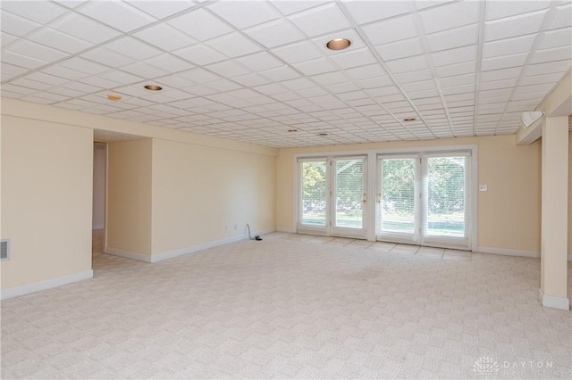 empty room featuring visible vents, baseboards, a drop ceiling, and light carpet