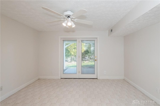 spare room featuring light carpet, a textured ceiling, baseboards, and a ceiling fan