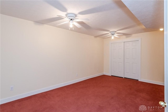 unfurnished bedroom with baseboards, carpet floors, a closet, a textured ceiling, and a ceiling fan