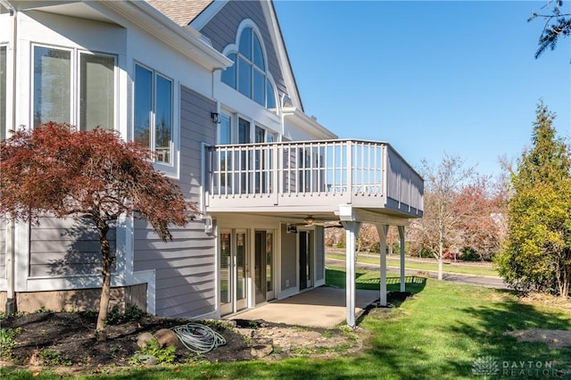 back of house featuring a patio, a yard, roof with shingles, and a wooden deck