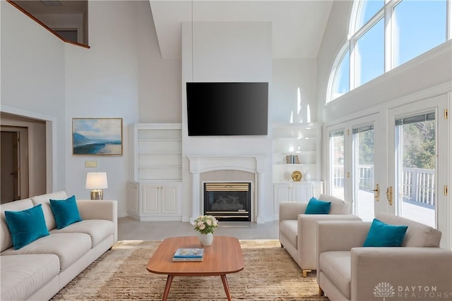 living area featuring a high ceiling and a glass covered fireplace