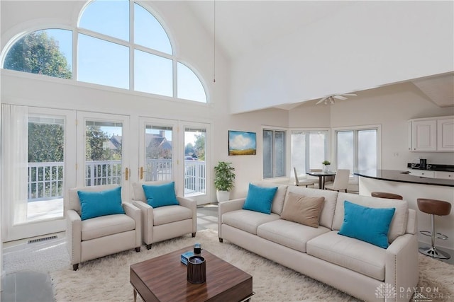 living area with visible vents, a towering ceiling, a ceiling fan, and french doors