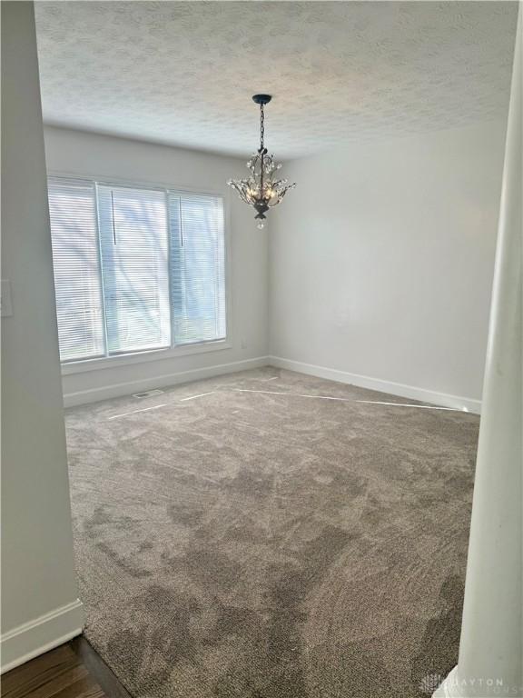 unfurnished room featuring baseboards, carpet floors, and a textured ceiling