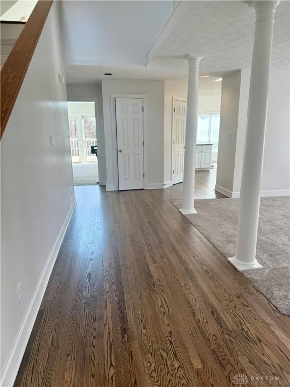 interior space featuring decorative columns, plenty of natural light, and wood finished floors