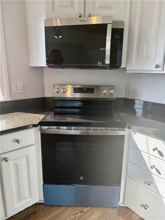 kitchen with white cabinetry, stainless steel appliances, and wood finished floors