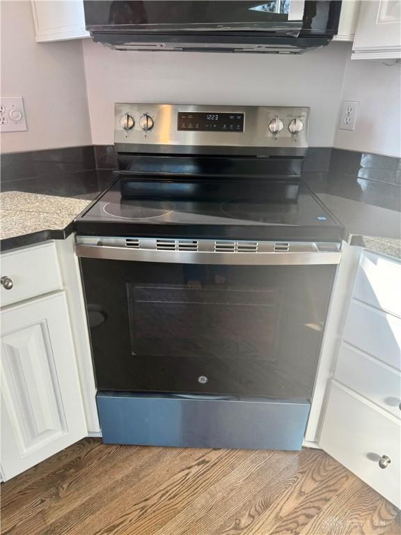 interior space featuring white cabinetry, stainless steel electric range oven, and under cabinet range hood