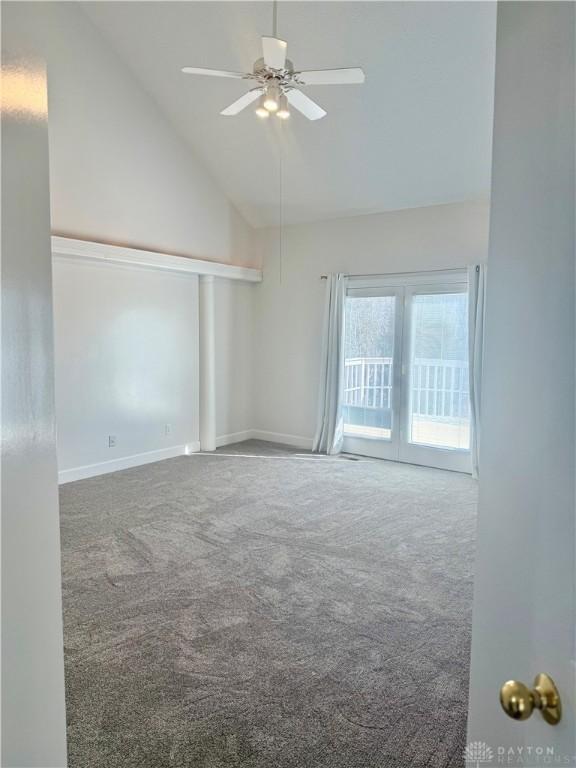 carpeted empty room featuring ceiling fan, baseboards, and high vaulted ceiling