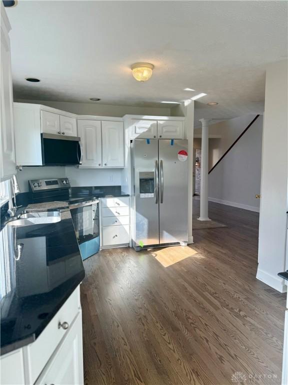 kitchen with dark countertops, white cabinets, stainless steel appliances, and dark wood-style flooring