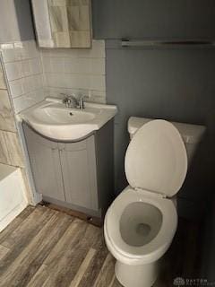 bathroom featuring a bathing tub, tasteful backsplash, wood-type flooring, toilet, and vanity