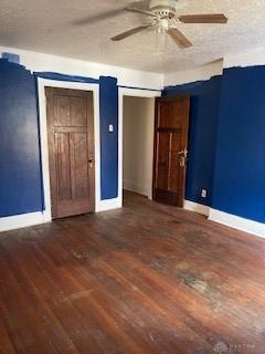 unfurnished room with a textured ceiling, ceiling fan, and dark wood-type flooring