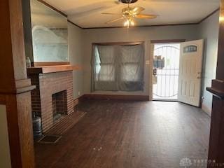 unfurnished living room with wood finished floors, visible vents, a ceiling fan, and a brick fireplace