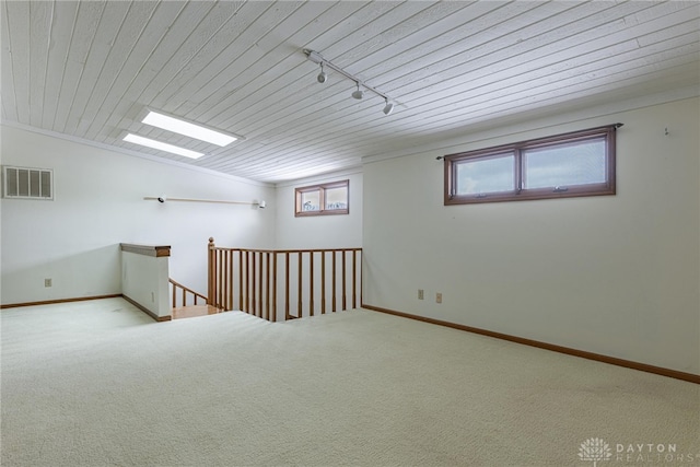 carpeted empty room featuring rail lighting, vaulted ceiling, and wood ceiling