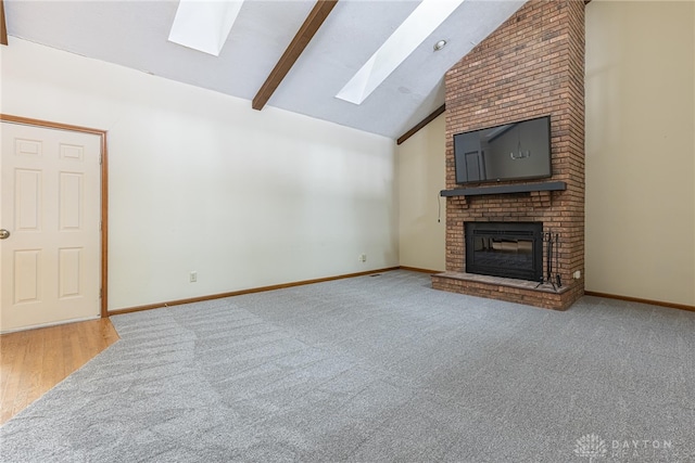 unfurnished living room with a fireplace and vaulted ceiling with skylight