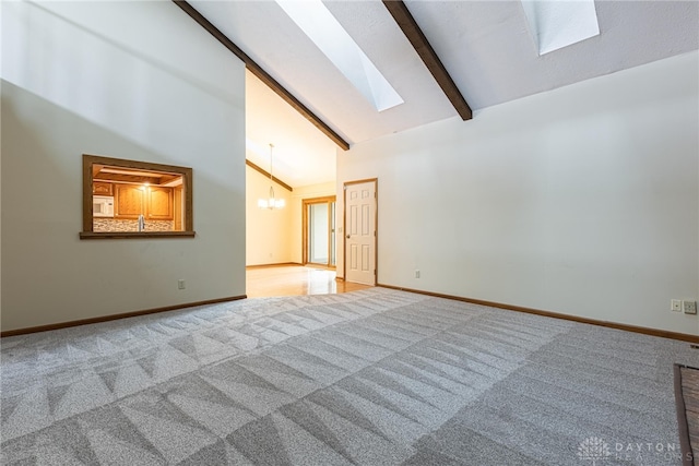 carpeted spare room featuring a notable chandelier, beam ceiling, high vaulted ceiling, and a skylight