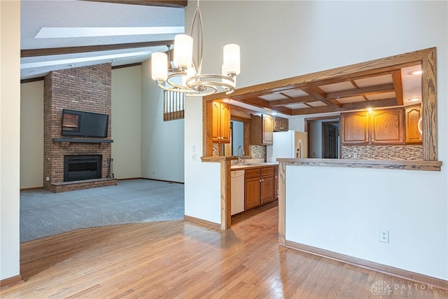 kitchen featuring an inviting chandelier, tasteful backsplash, pendant lighting, white appliances, and a fireplace