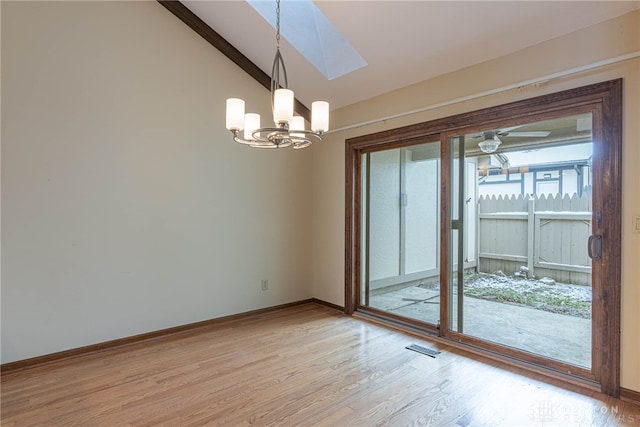 empty room featuring light hardwood / wood-style flooring, vaulted ceiling, and an inviting chandelier