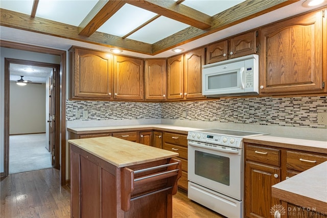 kitchen with backsplash, ceiling fan, white appliances, and hardwood / wood-style flooring