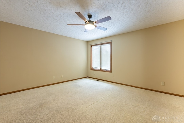 empty room featuring light carpet, ceiling fan, and a textured ceiling