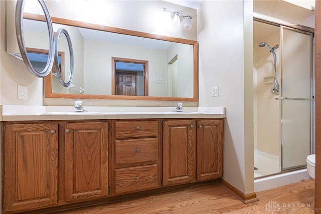 bathroom featuring a shower with door, vanity, hardwood / wood-style floors, and toilet