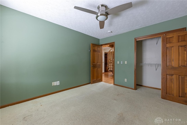 unfurnished bedroom with ceiling fan, a closet, light carpet, and a textured ceiling