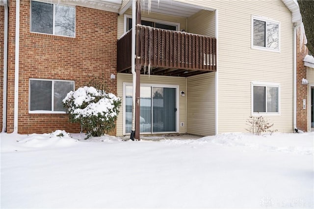 snow covered property entrance with a balcony