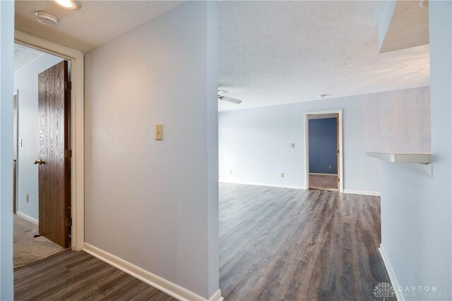 hallway with a textured ceiling and dark hardwood / wood-style floors