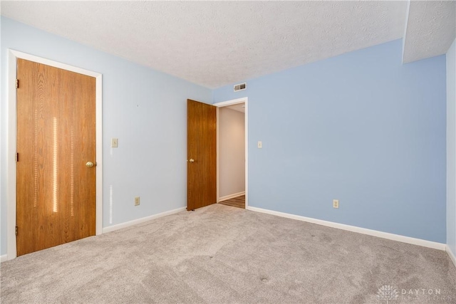 spare room with light carpet and a textured ceiling