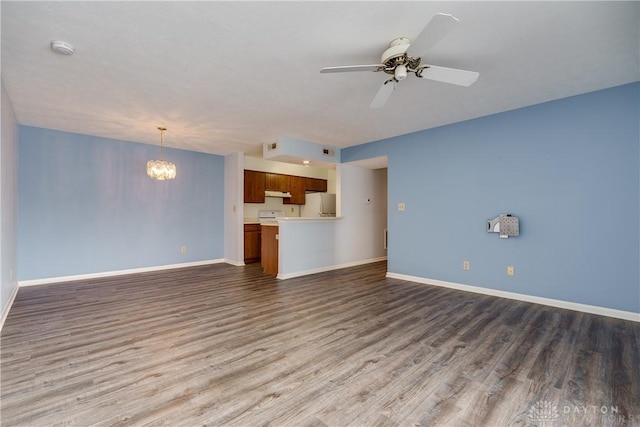 unfurnished living room featuring ceiling fan with notable chandelier and dark hardwood / wood-style flooring