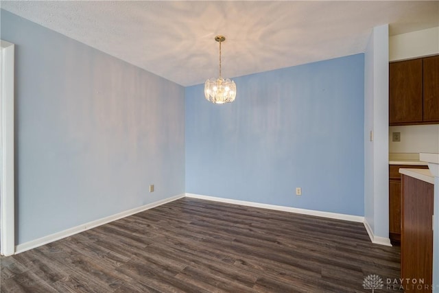 unfurnished dining area with dark wood-type flooring, a textured ceiling, and an inviting chandelier