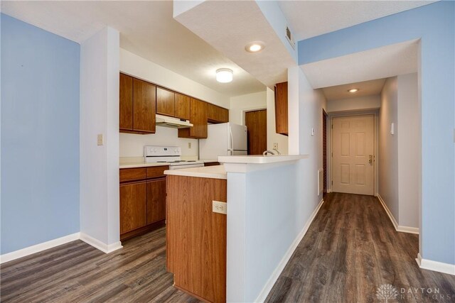 kitchen with kitchen peninsula, dark wood-type flooring, and white appliances