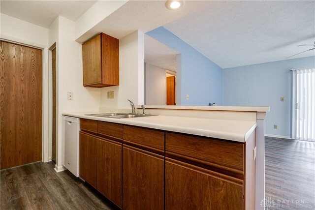 kitchen featuring kitchen peninsula, dark hardwood / wood-style flooring, white dishwasher, and sink