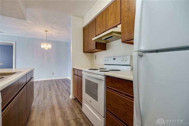 kitchen with white appliances, sink, decorative light fixtures, hardwood / wood-style flooring, and a chandelier