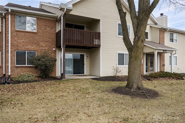 rear view of property with a balcony and a lawn