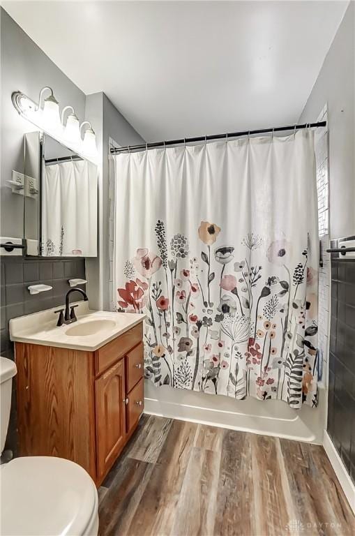 full bathroom featuring hardwood / wood-style flooring, vanity, toilet, and shower / bath combo with shower curtain