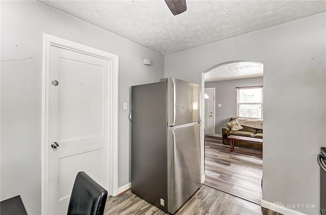 kitchen featuring a textured ceiling, light hardwood / wood-style flooring, stainless steel refrigerator, and ceiling fan