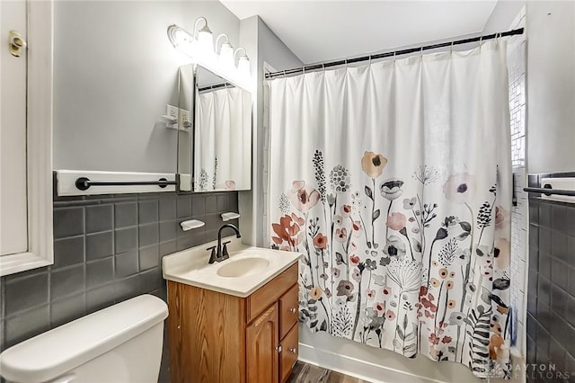 full bathroom with hardwood / wood-style floors, vanity, toilet, tile walls, and shower / tub combo