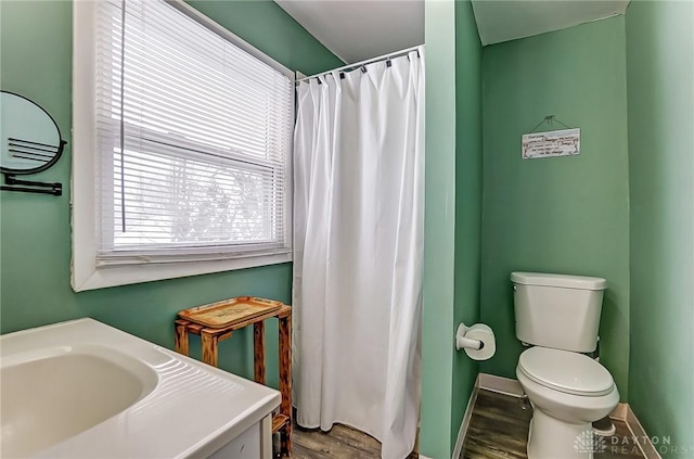 bathroom with hardwood / wood-style flooring, vanity, toilet, and walk in shower